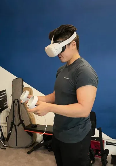 A man who wore a grey tee is experiencing virtual reality by using oculus rift headset