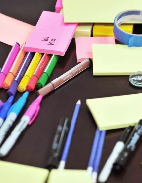 A dozens of colour pen and memo scattered on a black table