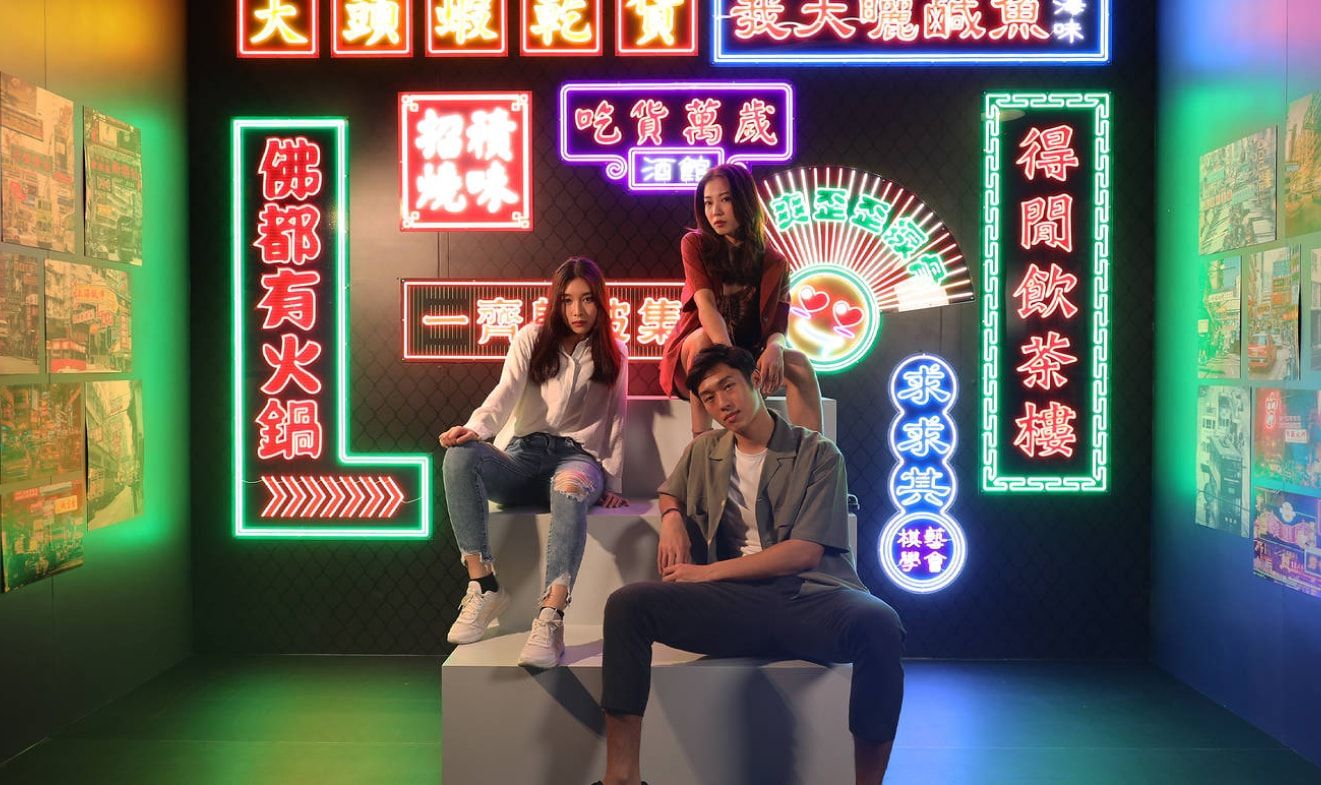 Three models are sitting on the main stage with a Hong Kong Streetscapes background for photo shooting